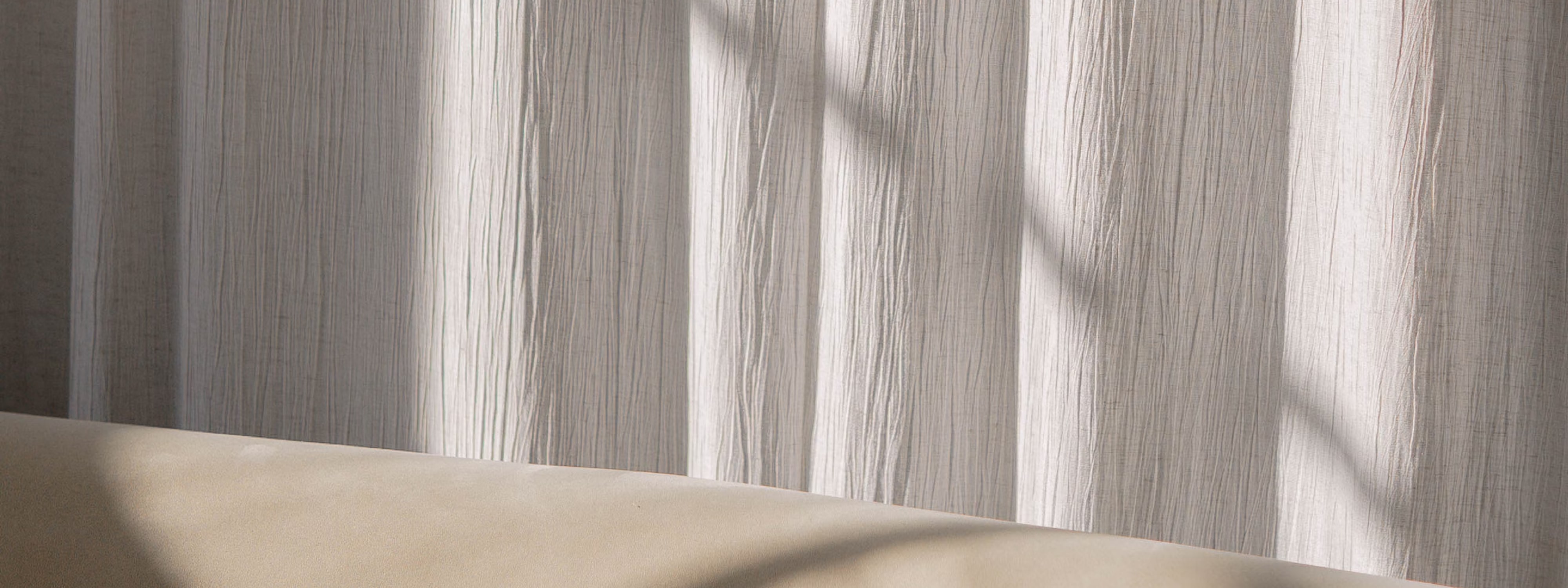 Soft light filtering through textured white curtains