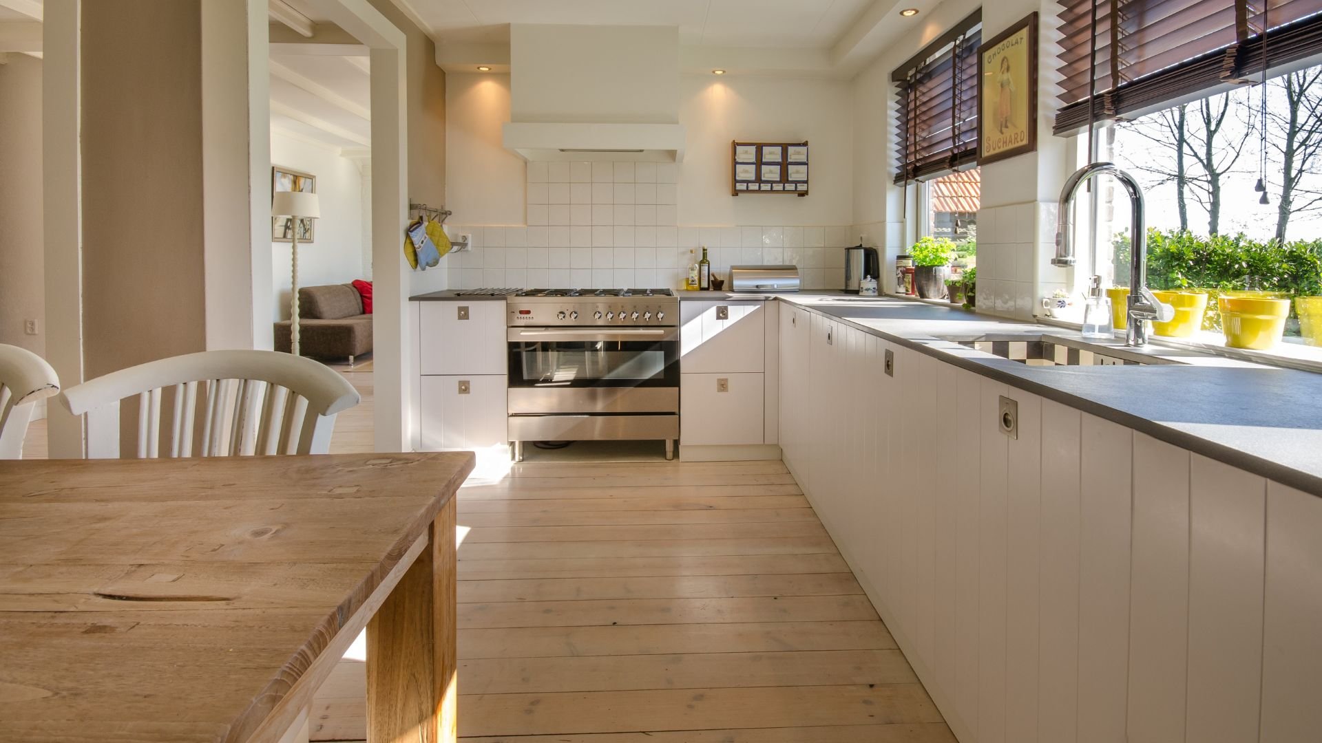 Bright modern kitchen with white cabinets, wooden floors, and large windows