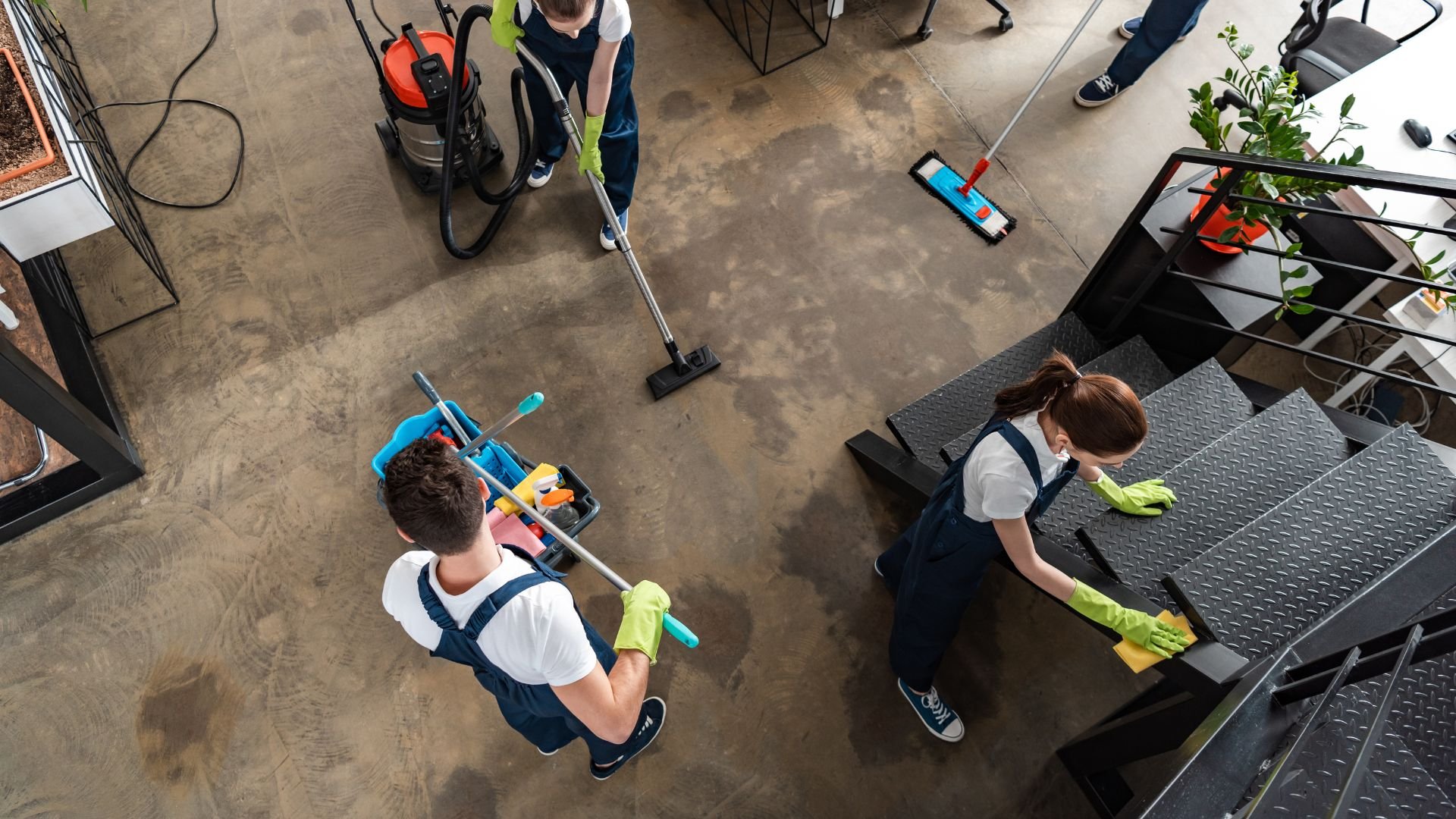 Cleaning staff with vacuum and mop working in an industrial or office space