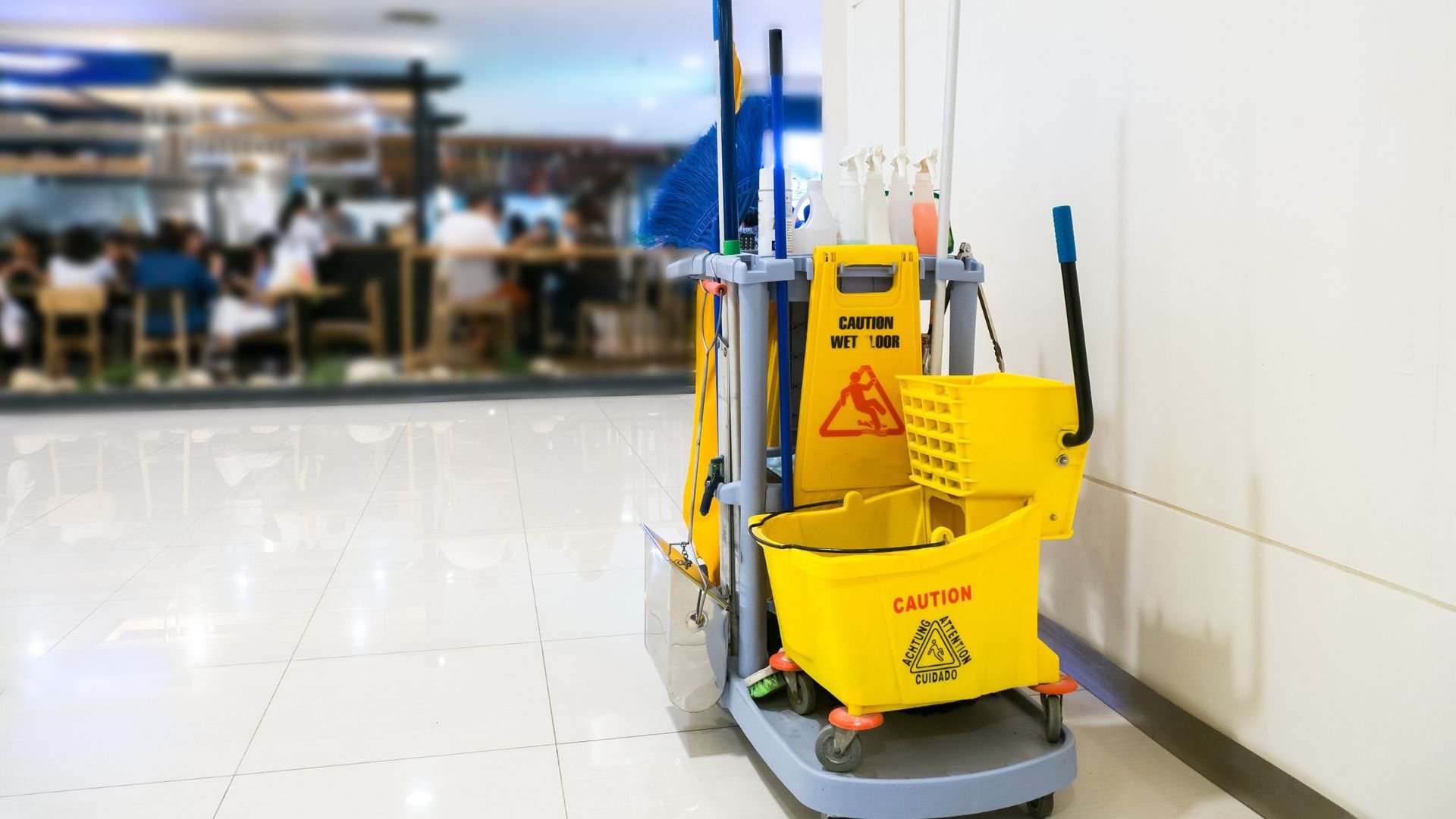 Yellow cleaning cart with mop, bucket, and wet floor caution sign