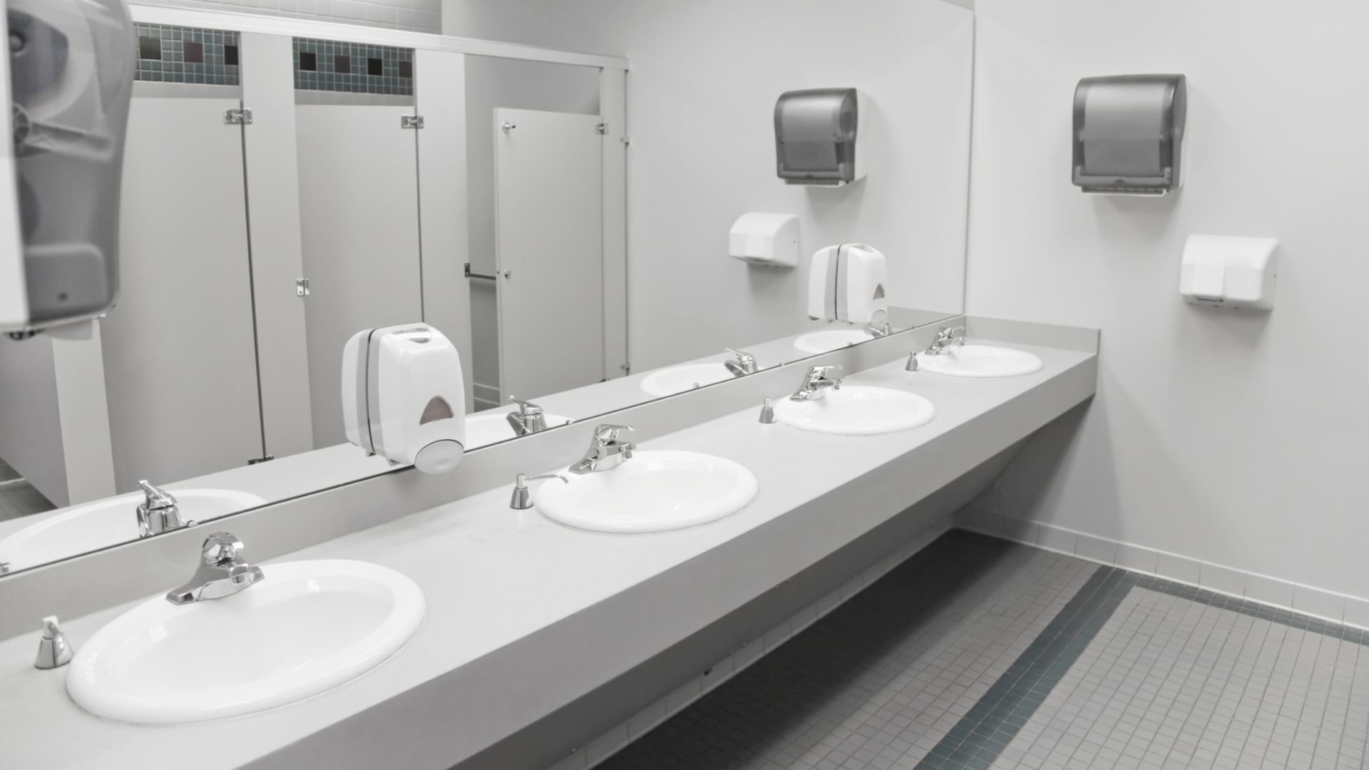 Clean public bathroom with multiple sinks, mirrors, and paper towel dispensers