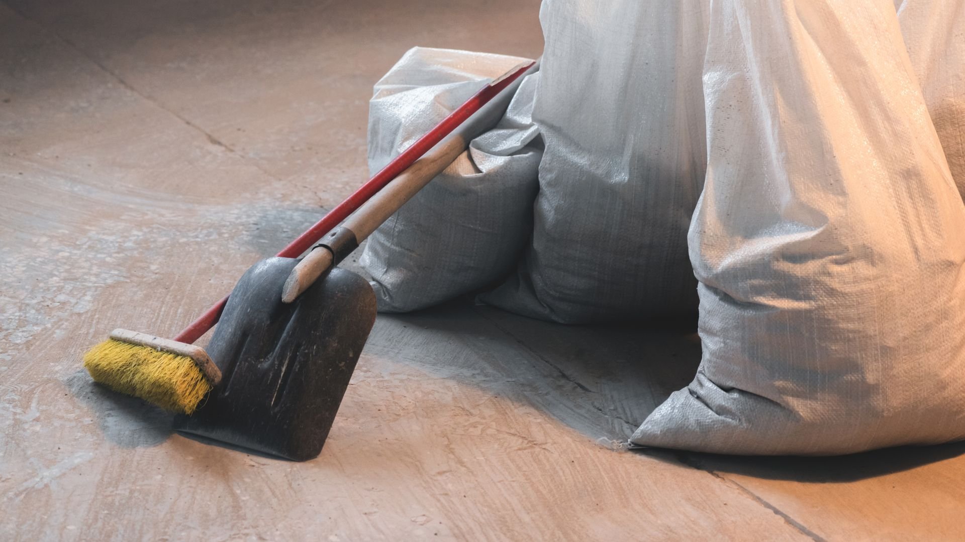 Dustpan, brush, and gray bags on wooden floor for cleaning