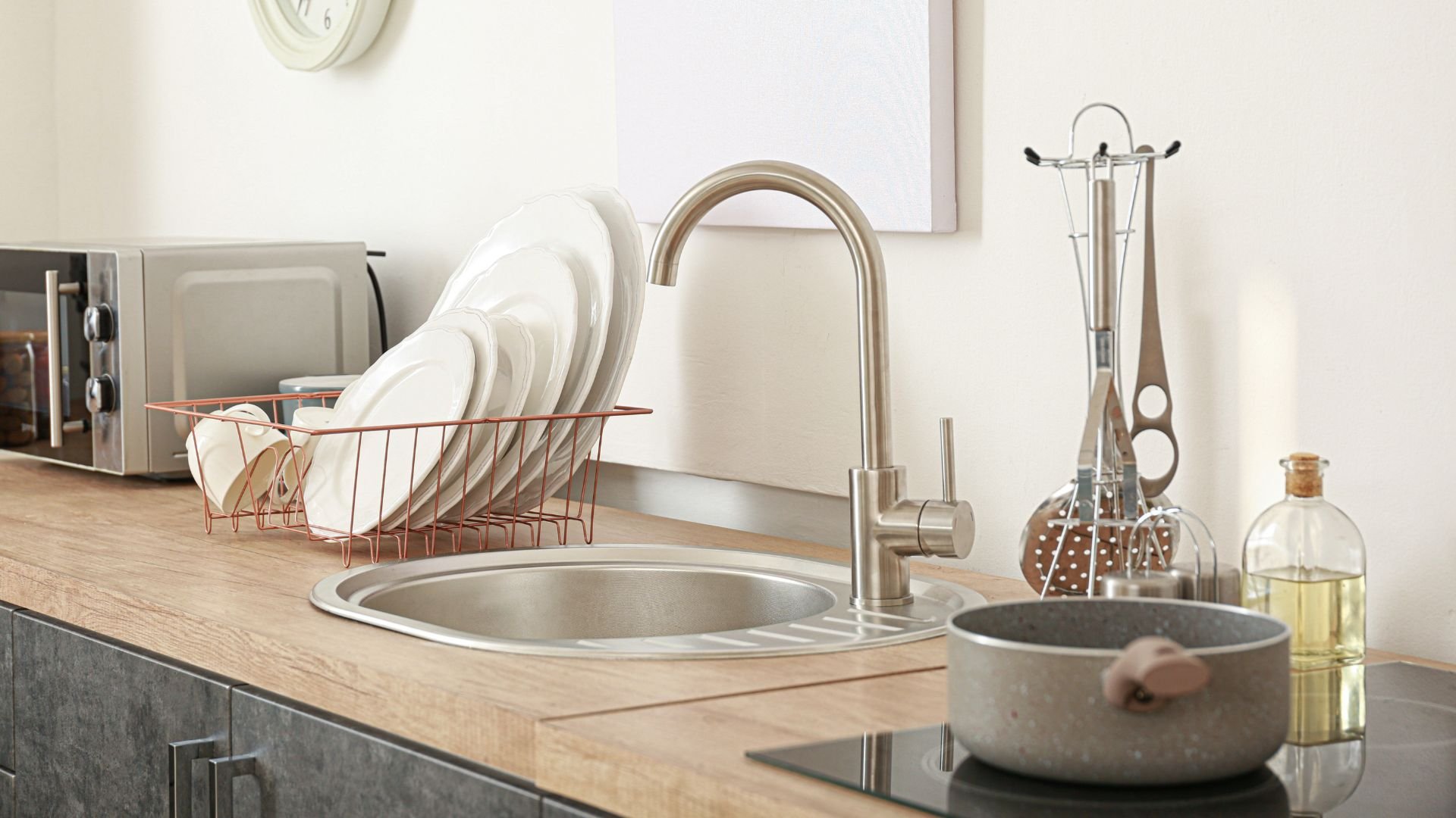 Modern kitchen sink with dishes, utensils, and cooking accessories